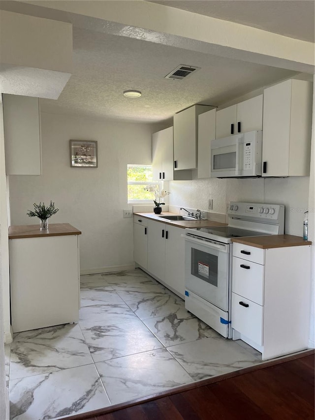 kitchen with white appliances, white cabinetry, a textured ceiling, and light wood-type flooring