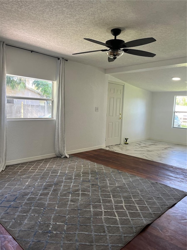 spare room with ceiling fan, a textured ceiling, and dark hardwood / wood-style flooring