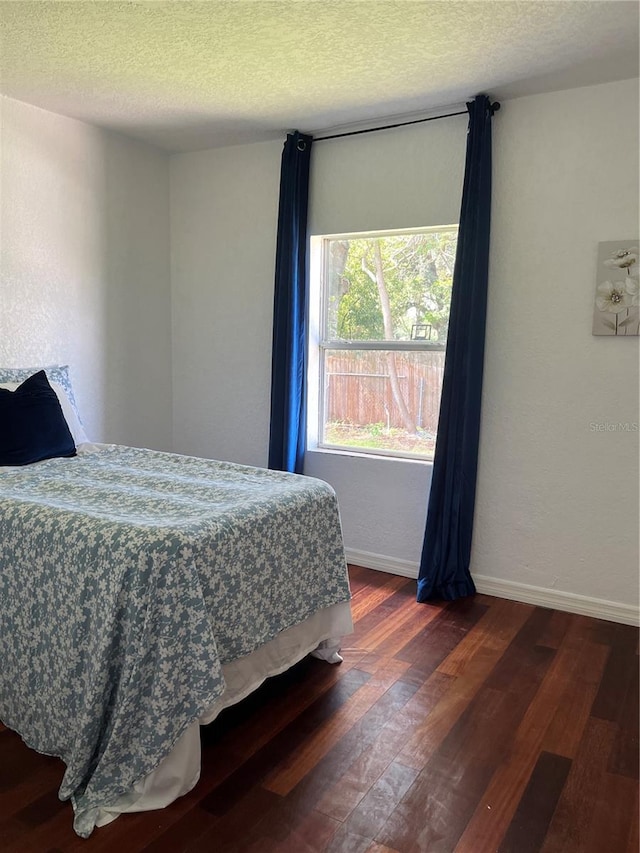 bedroom with dark wood-type flooring and a textured ceiling