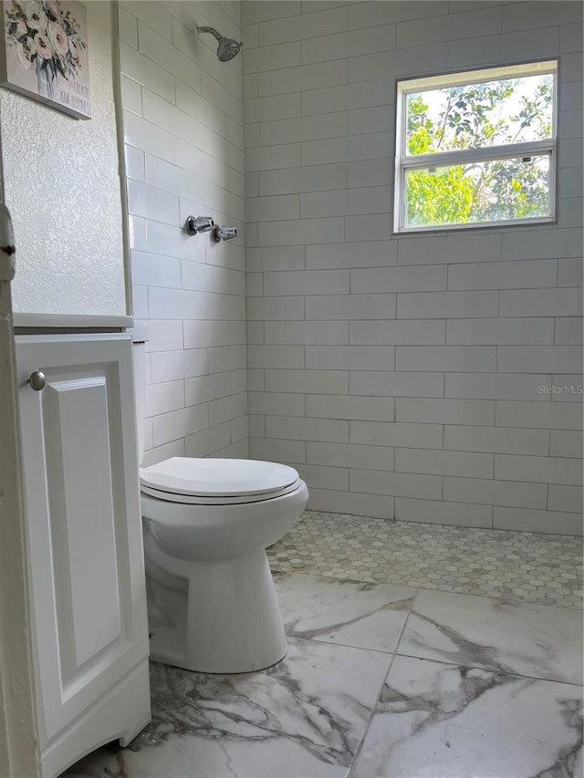 bathroom featuring a tile shower and toilet