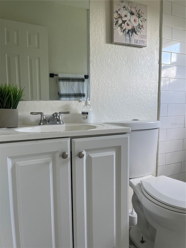 bathroom with toilet, vanity, and tile walls