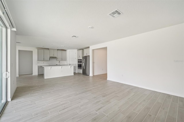 unfurnished living room with sink and light hardwood / wood-style flooring