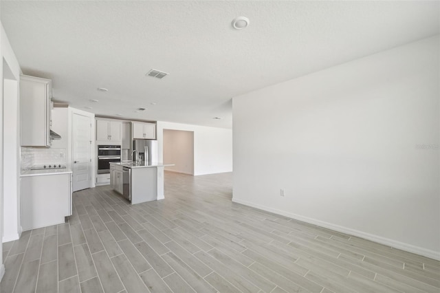 kitchen featuring a center island with sink, sink, tasteful backsplash, white cabinetry, and stainless steel appliances