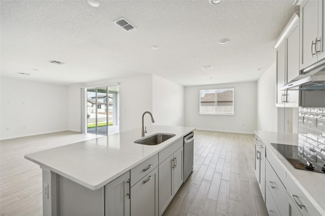 kitchen featuring a center island with sink, dishwasher, black electric cooktop, and sink