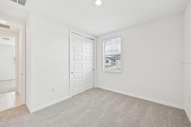 unfurnished bedroom featuring light carpet and a closet