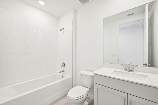 full bathroom featuring vanity, tiled shower / bath combo, hardwood / wood-style flooring, and toilet