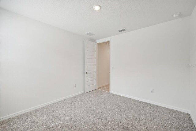 carpeted empty room with a textured ceiling