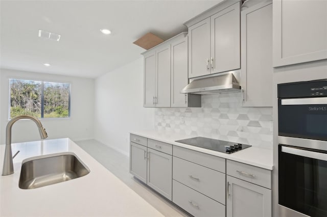 kitchen featuring sink, tasteful backsplash, double oven, gray cabinets, and black electric cooktop