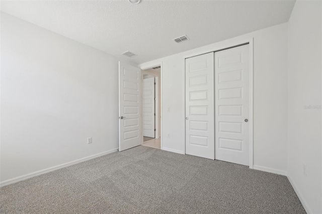 unfurnished bedroom featuring carpet floors, a textured ceiling, and a closet