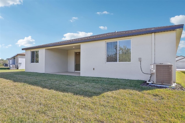 rear view of house with central AC unit, a patio, and a lawn