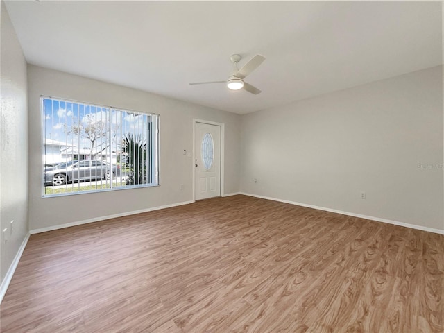 interior space with baseboards, a ceiling fan, and light wood-style flooring