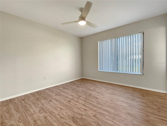 spare room with baseboards, ceiling fan, and wood finished floors