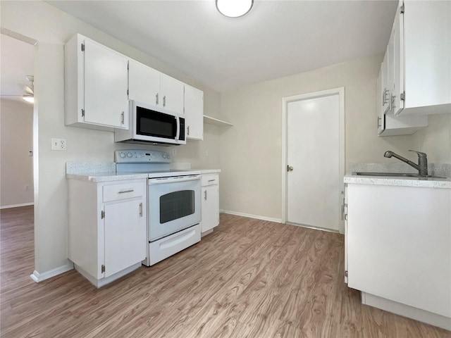 kitchen with a sink, light countertops, light wood-type flooring, and white appliances