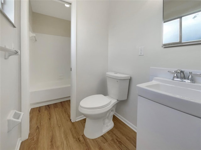 full bath featuring toilet, baseboards, wood finished floors, and vanity