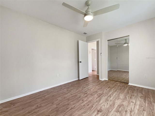 unfurnished bedroom with a ceiling fan, baseboards, wood finished floors, visible vents, and a closet