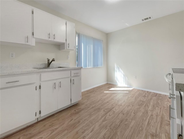 kitchen featuring light hardwood / wood-style flooring, sink, light stone counters, and white cabinets