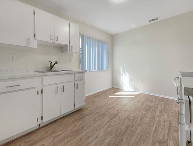 kitchen featuring visible vents, light wood-type flooring, a sink, light countertops, and white cabinets
