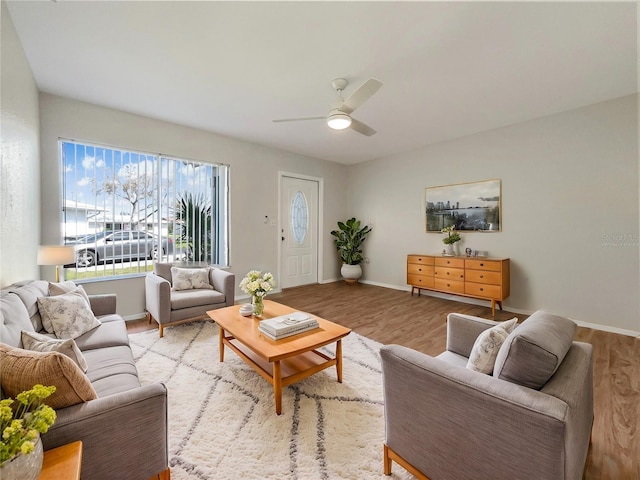 living room with light wood-style floors, baseboards, and a ceiling fan