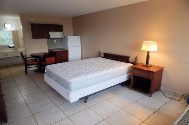 bedroom with light tile patterned flooring and white refrigerator