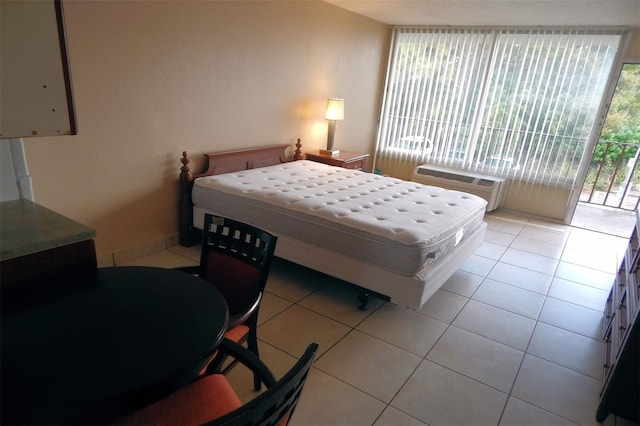 bedroom with a wall mounted AC, light tile patterned floors, and access to outside