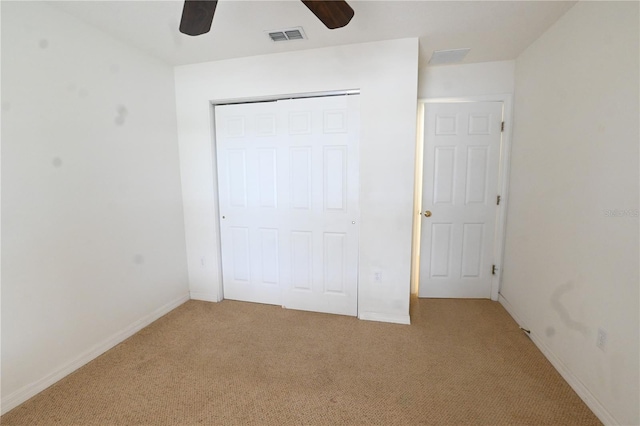 unfurnished bedroom featuring ceiling fan, light colored carpet, and a closet