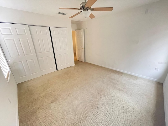 unfurnished bedroom with a closet, light colored carpet, and ceiling fan