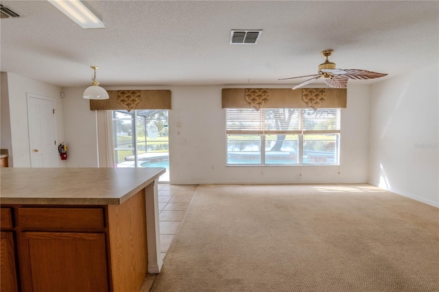 kitchen with ceiling fan, pendant lighting, light carpet, and a textured ceiling