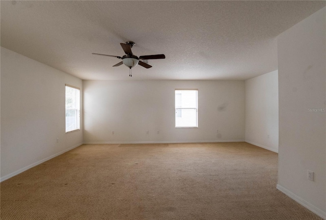 carpeted spare room featuring ceiling fan, a wealth of natural light, and a textured ceiling