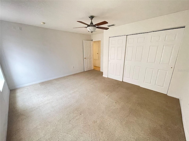 unfurnished bedroom featuring ceiling fan, a closet, and carpet