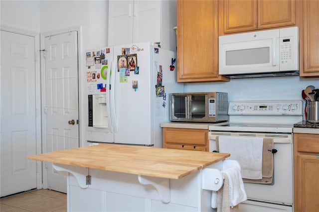 kitchen with light tile patterned floors, white appliances, butcher block counters, and a breakfast bar area