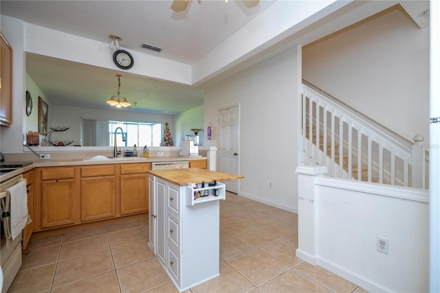 kitchen with light tile patterned floors, a center island, hanging light fixtures, and butcher block counters