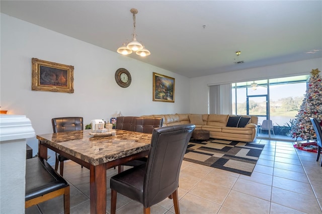 tiled dining room with ceiling fan with notable chandelier