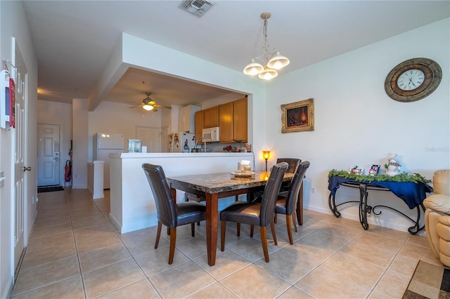 tiled dining area with ceiling fan with notable chandelier