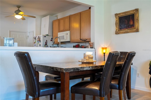 tiled dining space featuring ceiling fan