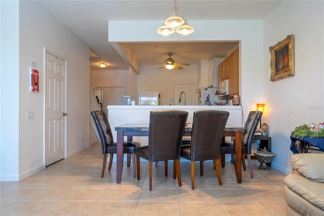 tiled dining room featuring ceiling fan and sink