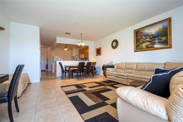 living room with light tile patterned flooring and ceiling fan with notable chandelier