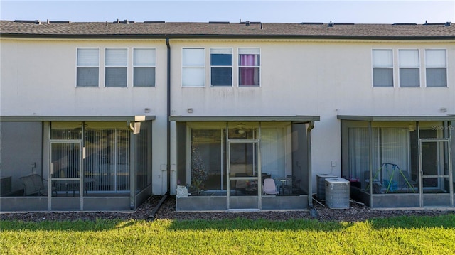 rear view of property featuring central air condition unit, a sunroom, and a yard