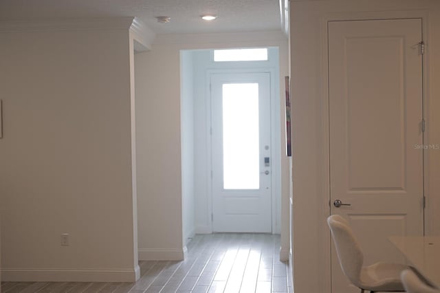 doorway to outside with crown molding, light wood-type flooring, and a textured ceiling