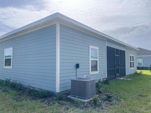 view of home's exterior with central AC unit, a sunroom, and a yard