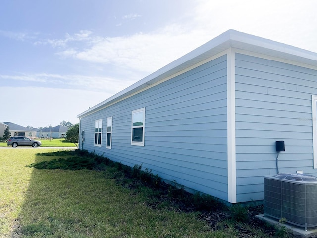 view of side of home featuring a lawn and central AC unit