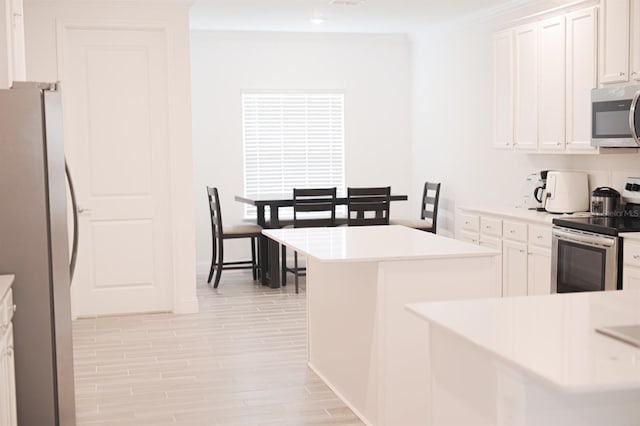 kitchen with kitchen peninsula, appliances with stainless steel finishes, ornamental molding, light hardwood / wood-style flooring, and white cabinetry