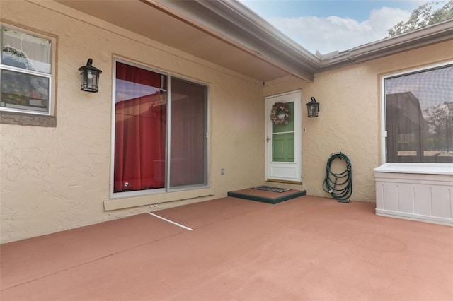 view of exterior entry featuring a patio and stucco siding