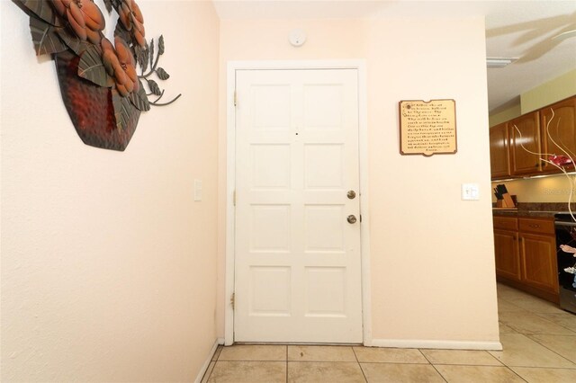 entryway with baseboards and light tile patterned flooring