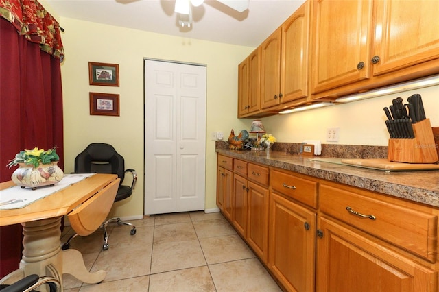 kitchen with built in desk, ceiling fan, and light tile patterned floors