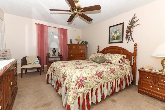 bedroom featuring a textured ceiling, light colored carpet, and ceiling fan