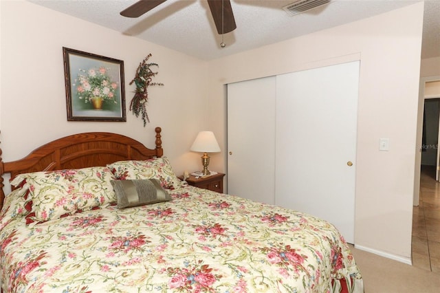 carpeted bedroom with a textured ceiling, a closet, and ceiling fan