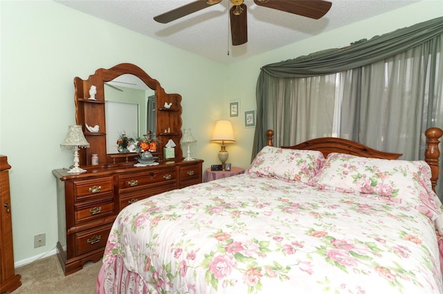 bedroom with light colored carpet, ceiling fan, baseboards, and a textured ceiling