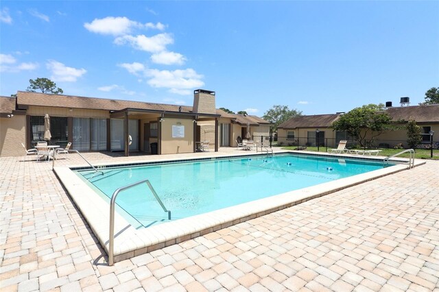 community pool with a patio area and fence