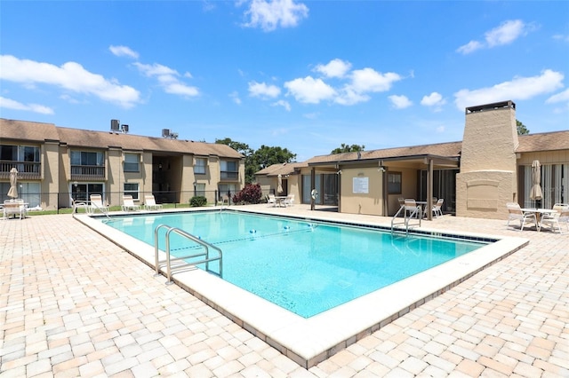 community pool with fence and a patio area
