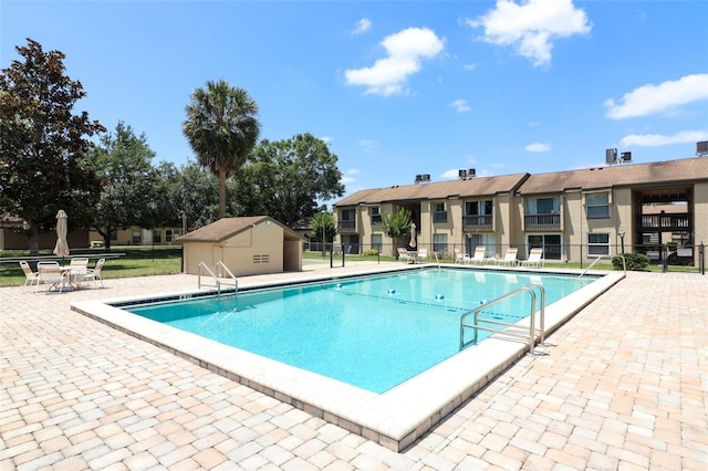 view of swimming pool featuring a patio and a storage unit